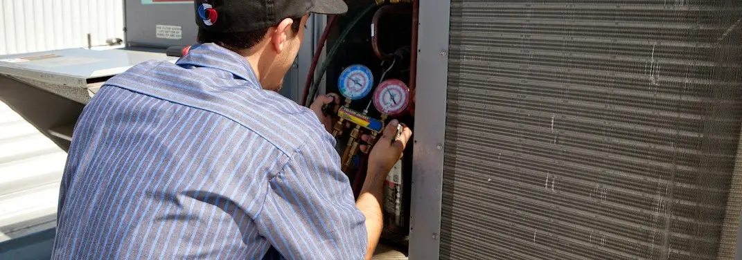 HVAC technician servicing a condenser unit in Purcellville